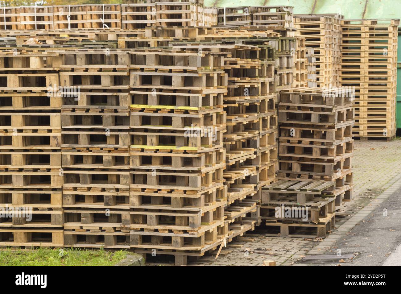 De nombreuses palettes en bois sont empilées les unes sur les autres et forment un mur dans une salle de stockage Banque D'Images