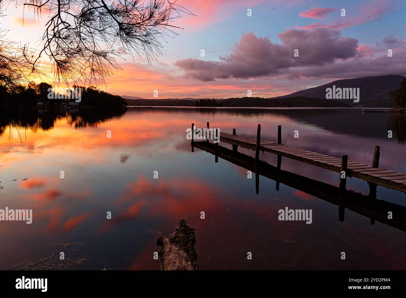 Coucher de soleil pittoresque et reflets sur le lac avec l'ancienne jetée Banque D'Images