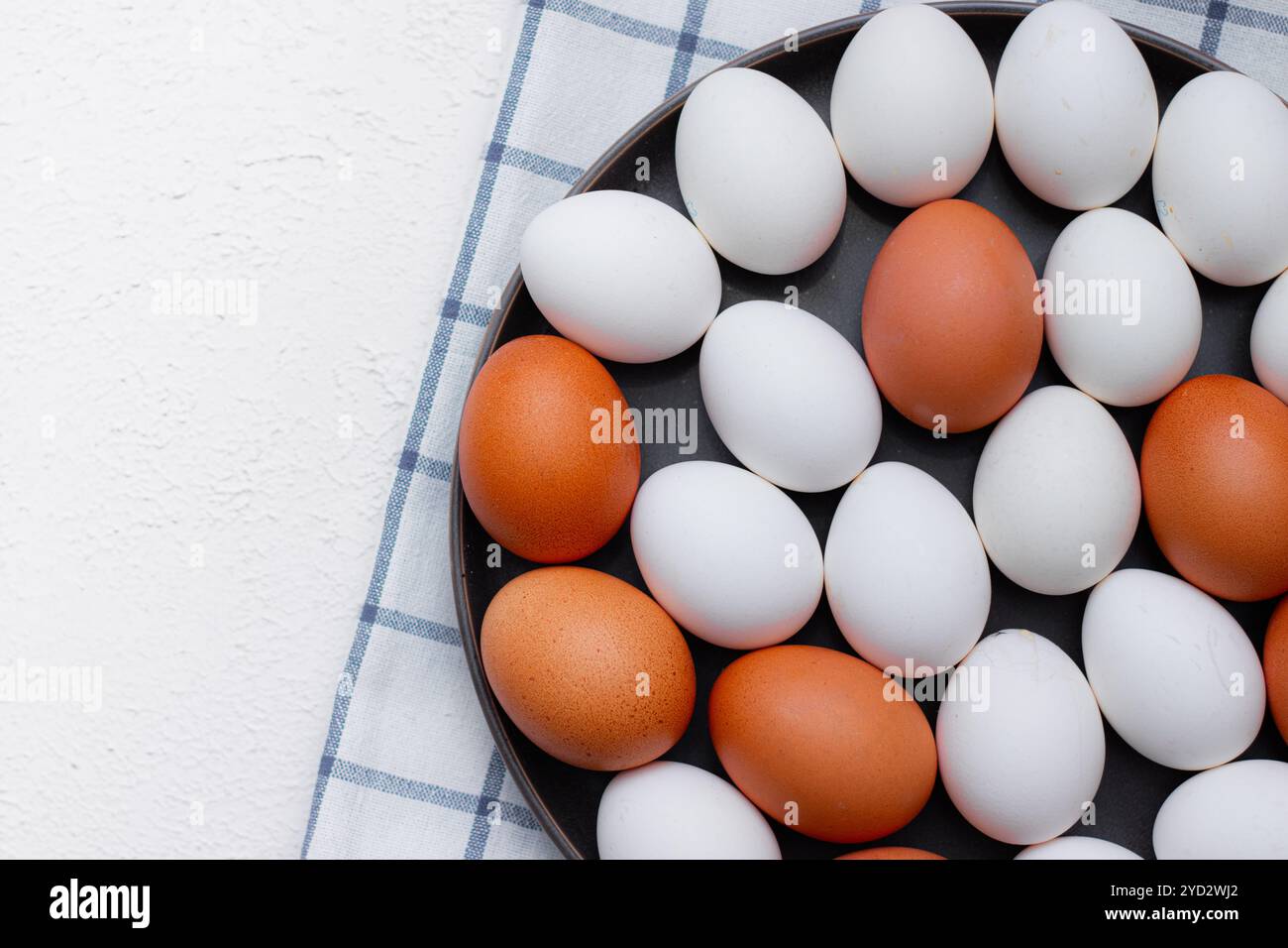 Oeufs de poule sur une serviette de cuisine à carreaux sur une table lumineuse. concept de produits agricoles et d'aliments naturels. Article sur les produits pour la maison Banque D'Images