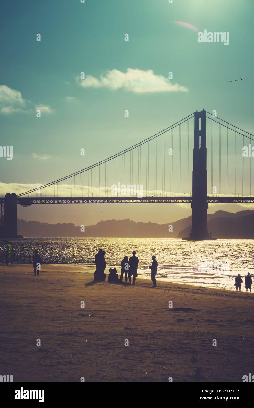 La silhouette d'un groupe d'amis sur la plage sous le Golden Gate Bridge San Francisco Banque D'Images