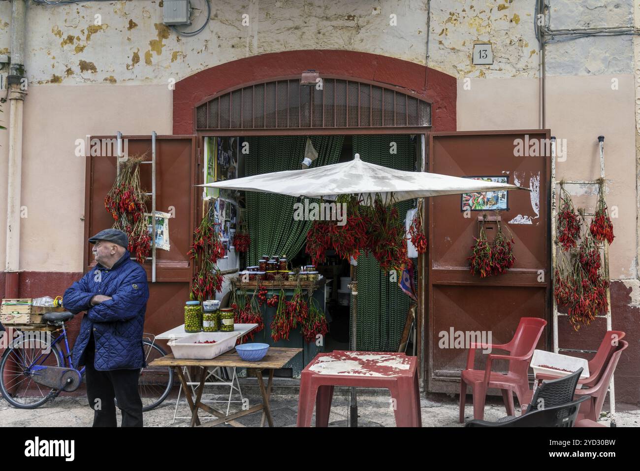 Bari, Italie, 27 novembre 2023 : magasin du coin à Bari Vecchio avec un vieil homme vendant des piments et des olives, Europe Banque D'Images