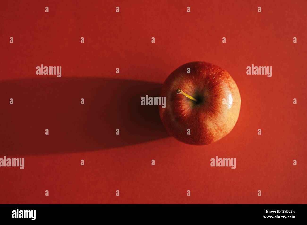 Pomme rouge formant une ombre contre le dos rouge Banque D'Images