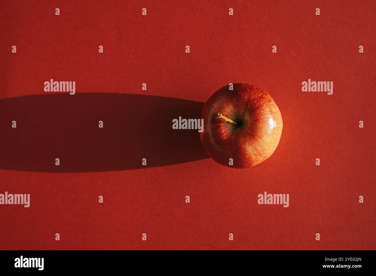 Pomme rouge formant une ombre contre le dos rouge Banque D'Images