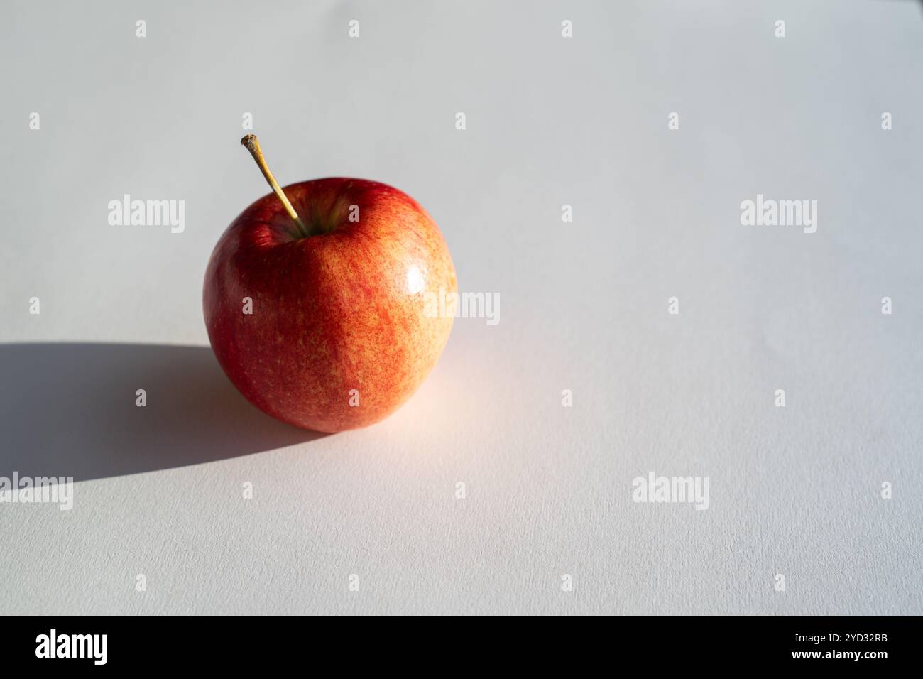 Pomme rouge formant une ombre sur le dos blanc Banque D'Images
