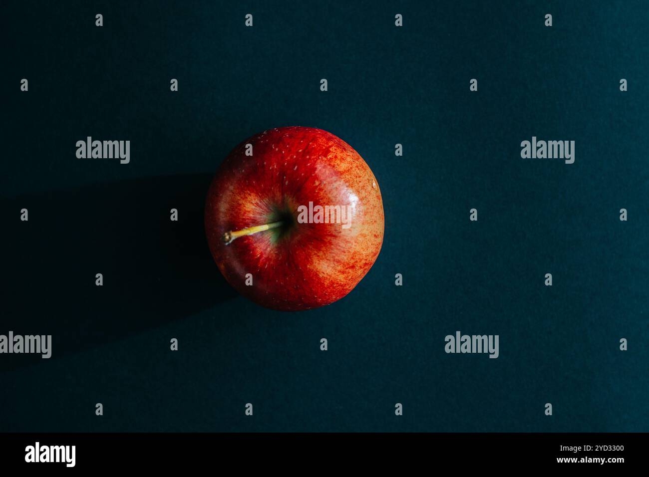 Pomme rouge formant une ombre contre le dos noir Banque D'Images