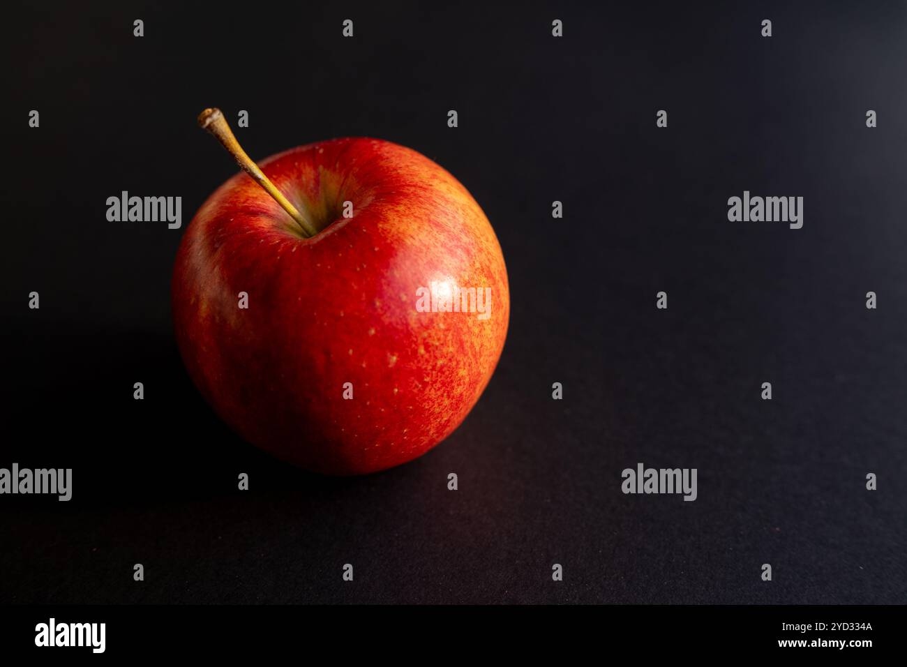 Pomme rouge formant une ombre contre le dos noir Banque D'Images