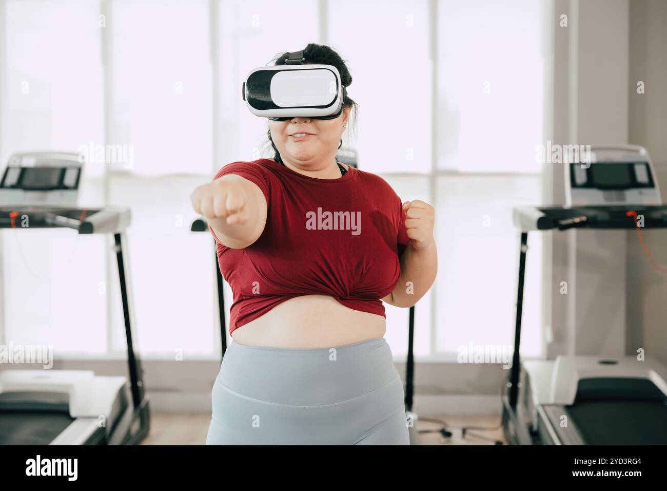 Femme utilisant un casque VR pour une expérience d'entraînement dans la salle de gym moderne. fitness, technologie et concept de motivation. Banque D'Images