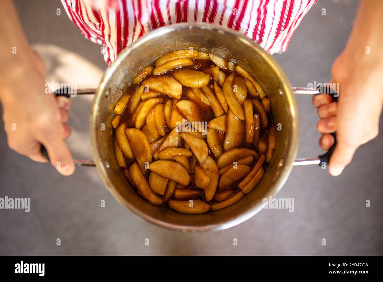 Mains de l'homme tenant un pot en argent de remplissage de tarte aux pommes maison Banque D'Images