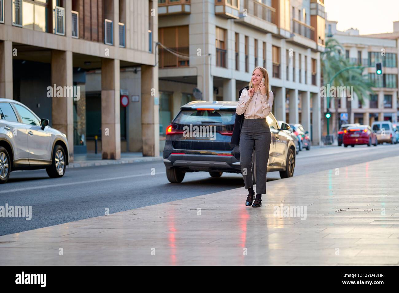 Femme d'affaires marchant et parlant au téléphone dans une ville animée Banque D'Images