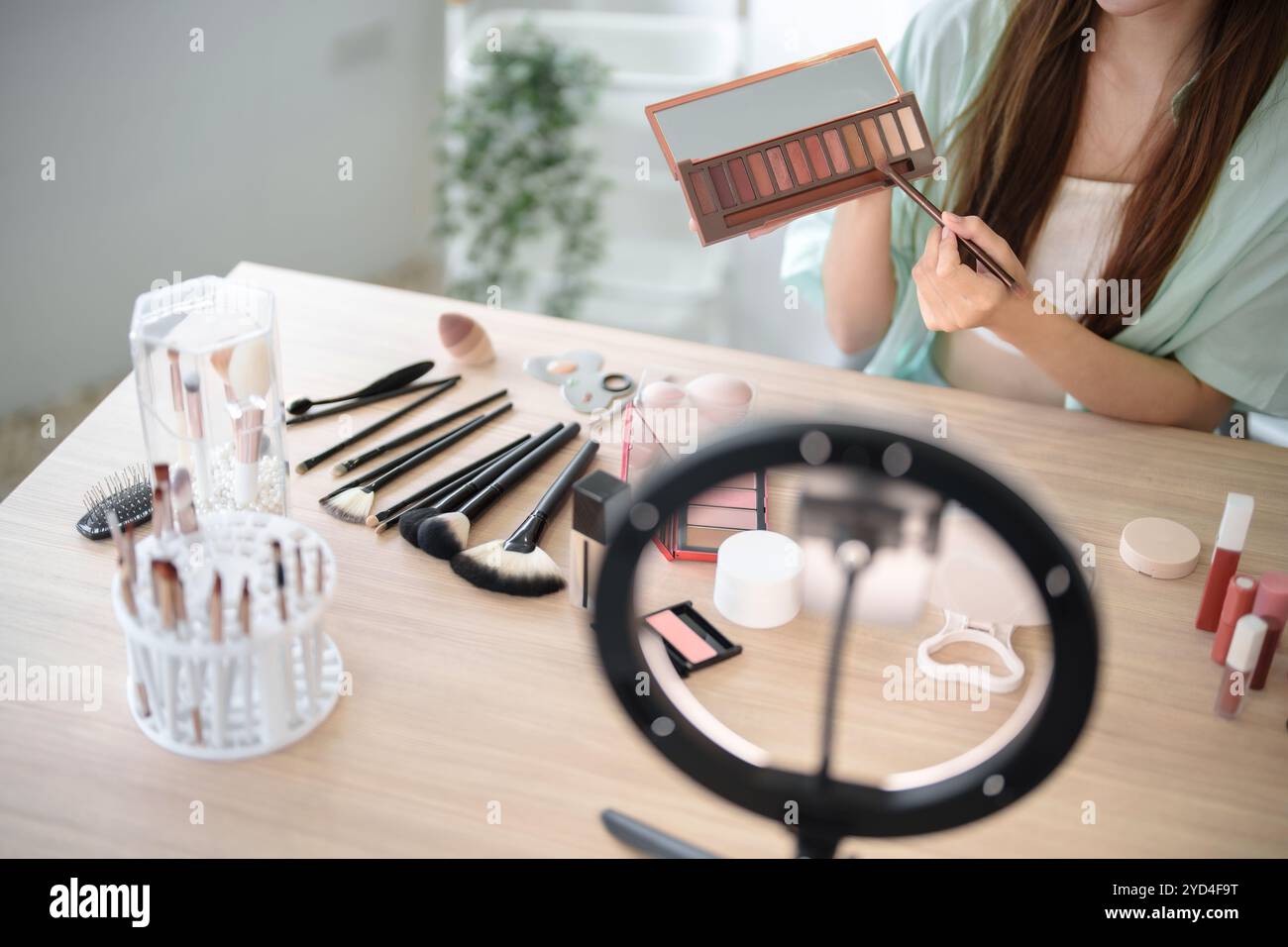 Charmante vlogger asiatique montrant des produits cosmétiques conseils pour son blog beauté en ligne. Banque D'Images