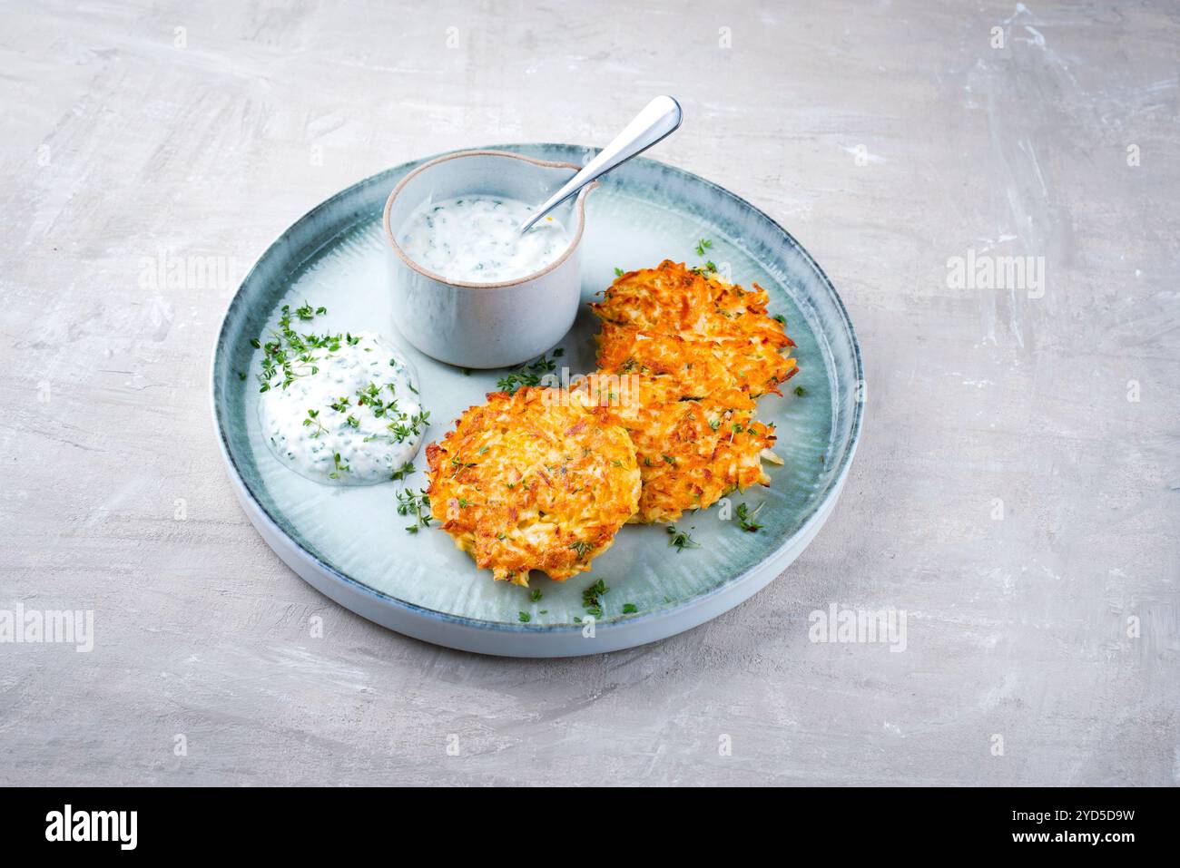 Crêpes de pommes de terre au panais traditionnelles avec ciboulette et sauce au fromage blanc servies en gros plan sur une assiette Nordic Design avec espace texte Banque D'Images