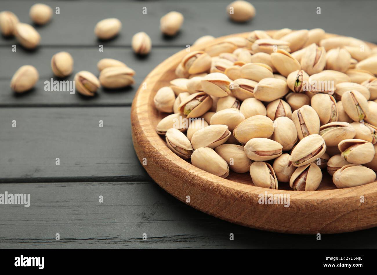 Pistaches salées pour la bière sur fond noir. Délicieuses pistaches saines dans une assiette en bois. Vue de dessus Banque D'Images