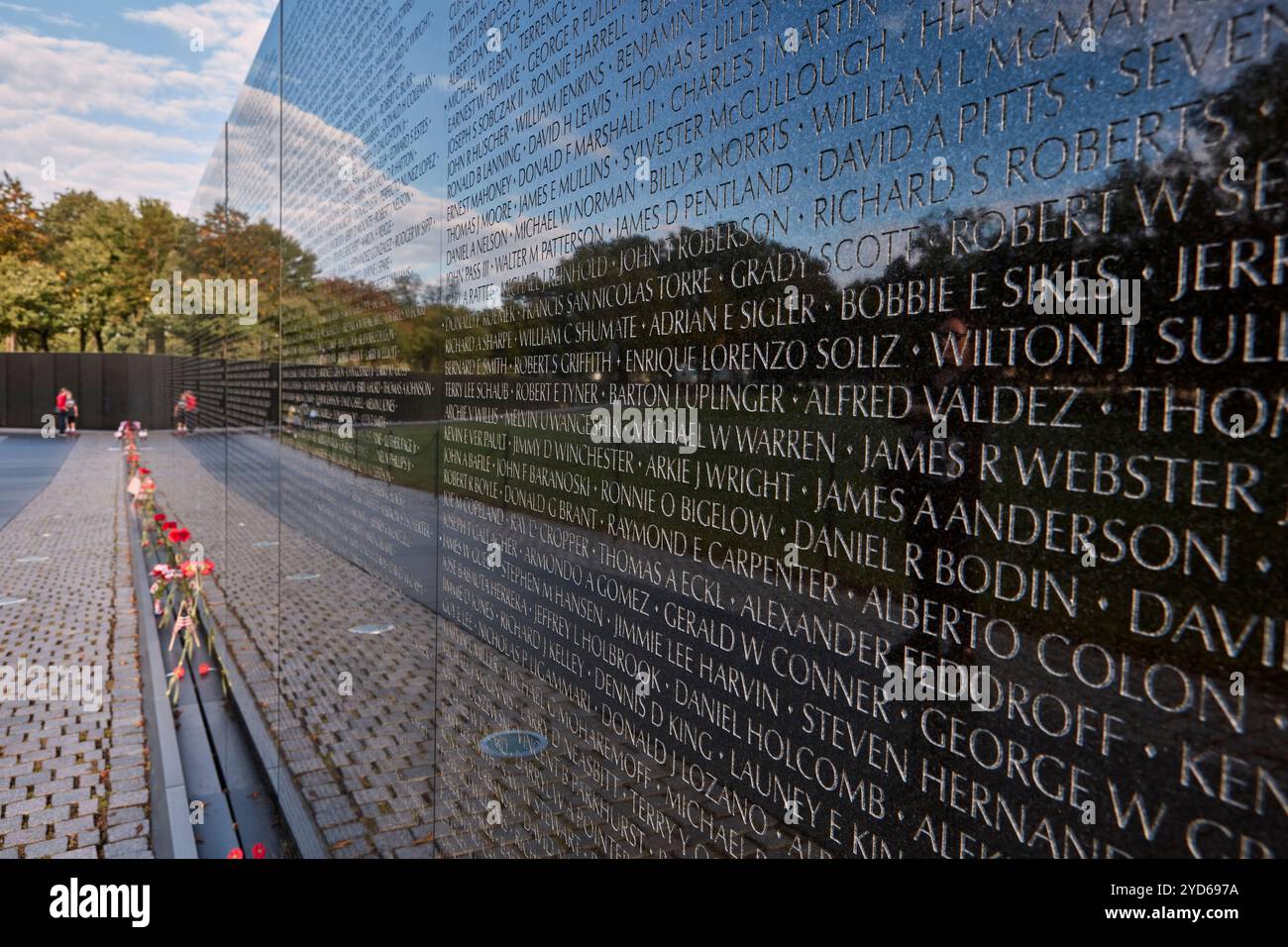 Le Vietnam Veterans Memorial à Washington D.C. présente des noms gravés dans le granit. Les fleurs honorent les soldats tombés dans un environnement tranquille. Banque D'Images