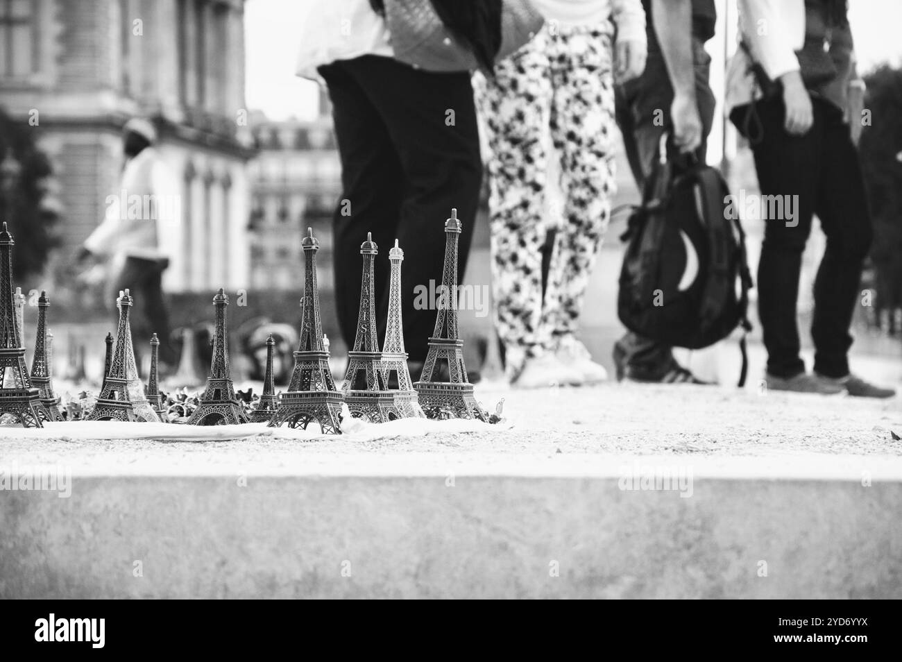 Statuettes de la tour Eiffel à vendre près du musée du Louvre et figures floues de touristes en arrière-plan. Photo noir et blanc. Banque D'Images