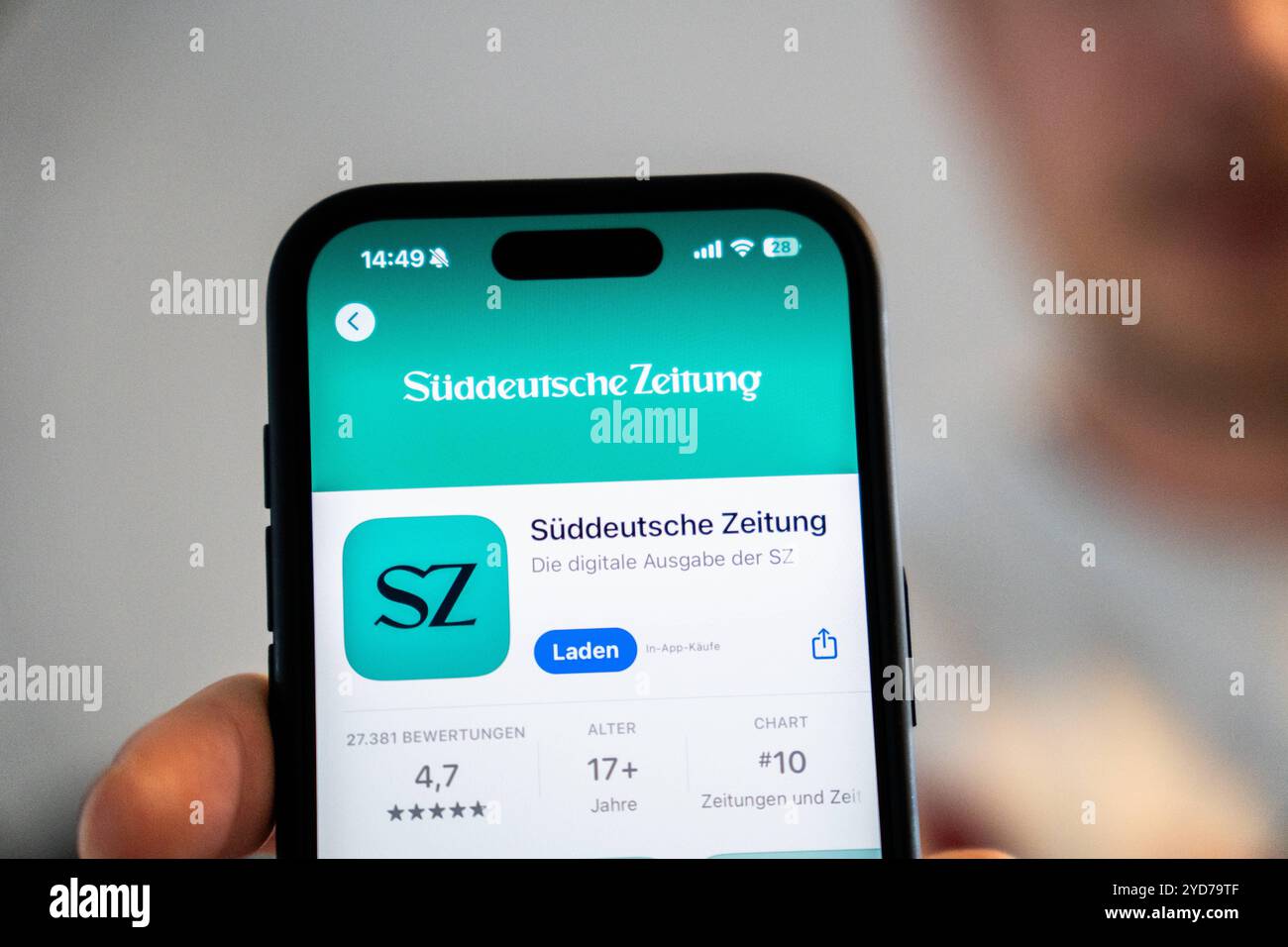 Bavière, Allemagne - 25 octobre 2024 : un homme tient un iPhone avec l'application Süddeutsche Zeitung SZ dans l'Appstore. Image symbolique arrêt des éditions imprimées locales et fermeture des bureaux de rédaction locaux *** Ein Mann hält ein iPhone mit der App Süddeutsche Zeitung Sz im Appstore. Symbolbild Einstellung der lokalen Printausgaben und schließung der Lokalredaktionen Banque D'Images
