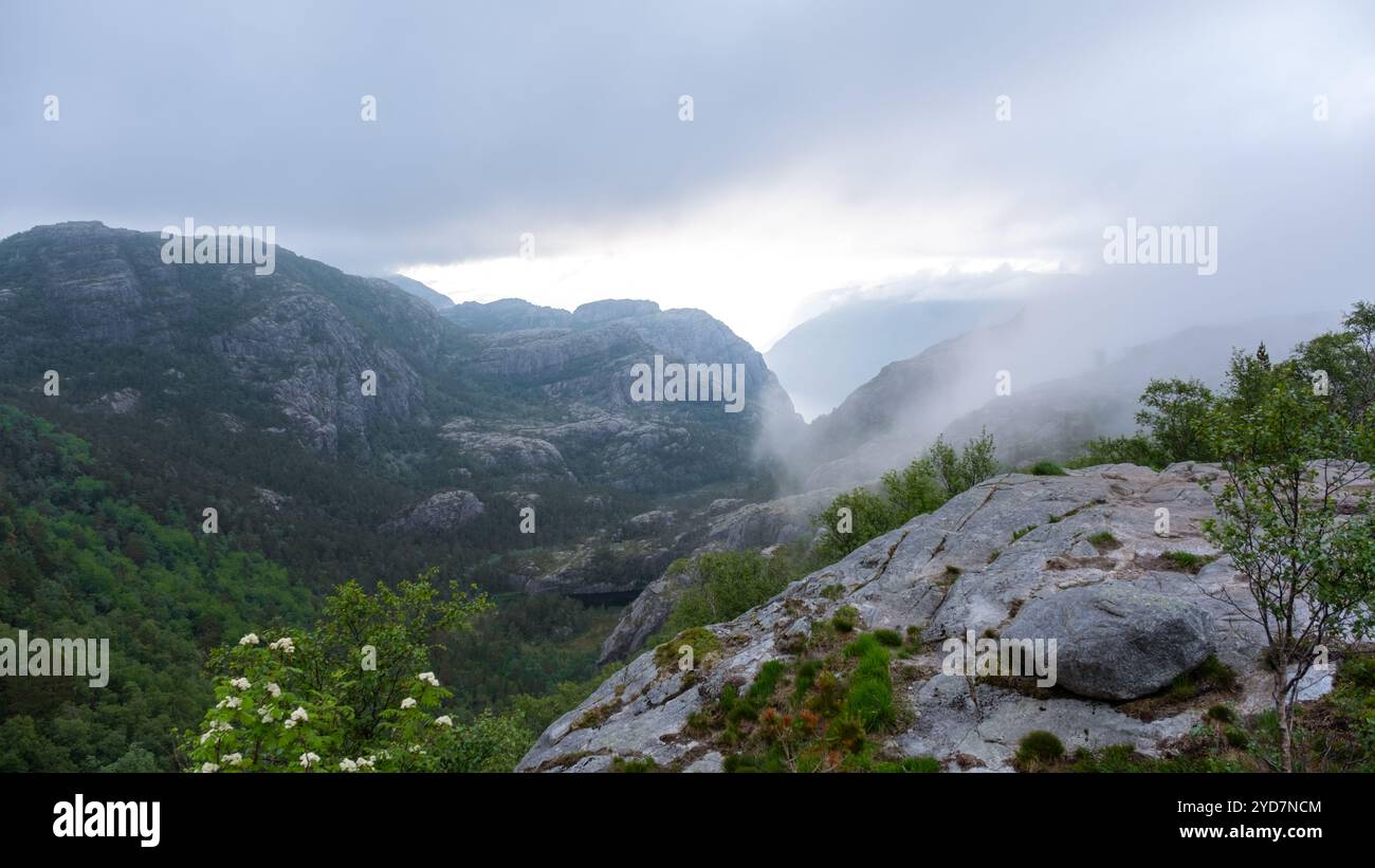 Une vue d'une vallée de montagne brumeuse en Norvège un jour d'été. La vallée est entourée de brouillard, avec les sommets du Mo environnant Banque D'Images