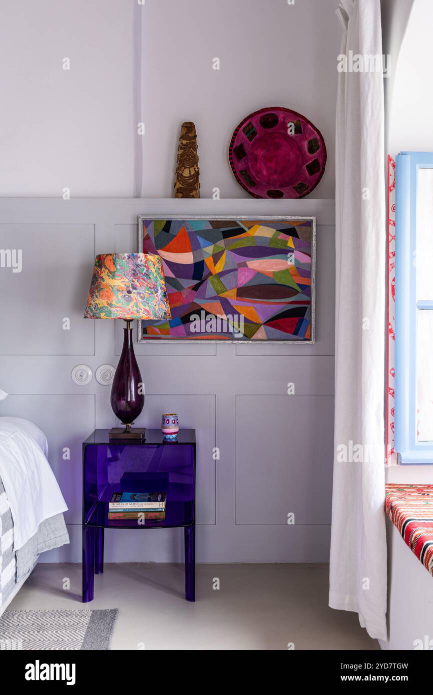 Lampe sur table de chevet violette avec art moderne dans une maison historique sur l'île de Tinos en Grèce Banque D'Images
