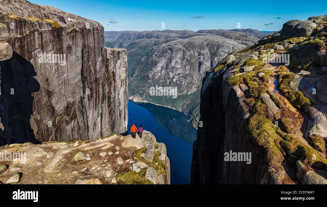 Deux personnes se tiennent sur le bord du Kjeragbolten, Norway Pulpit Rock en Norvège, regardant sur le paysage magnifique Banque D'Images