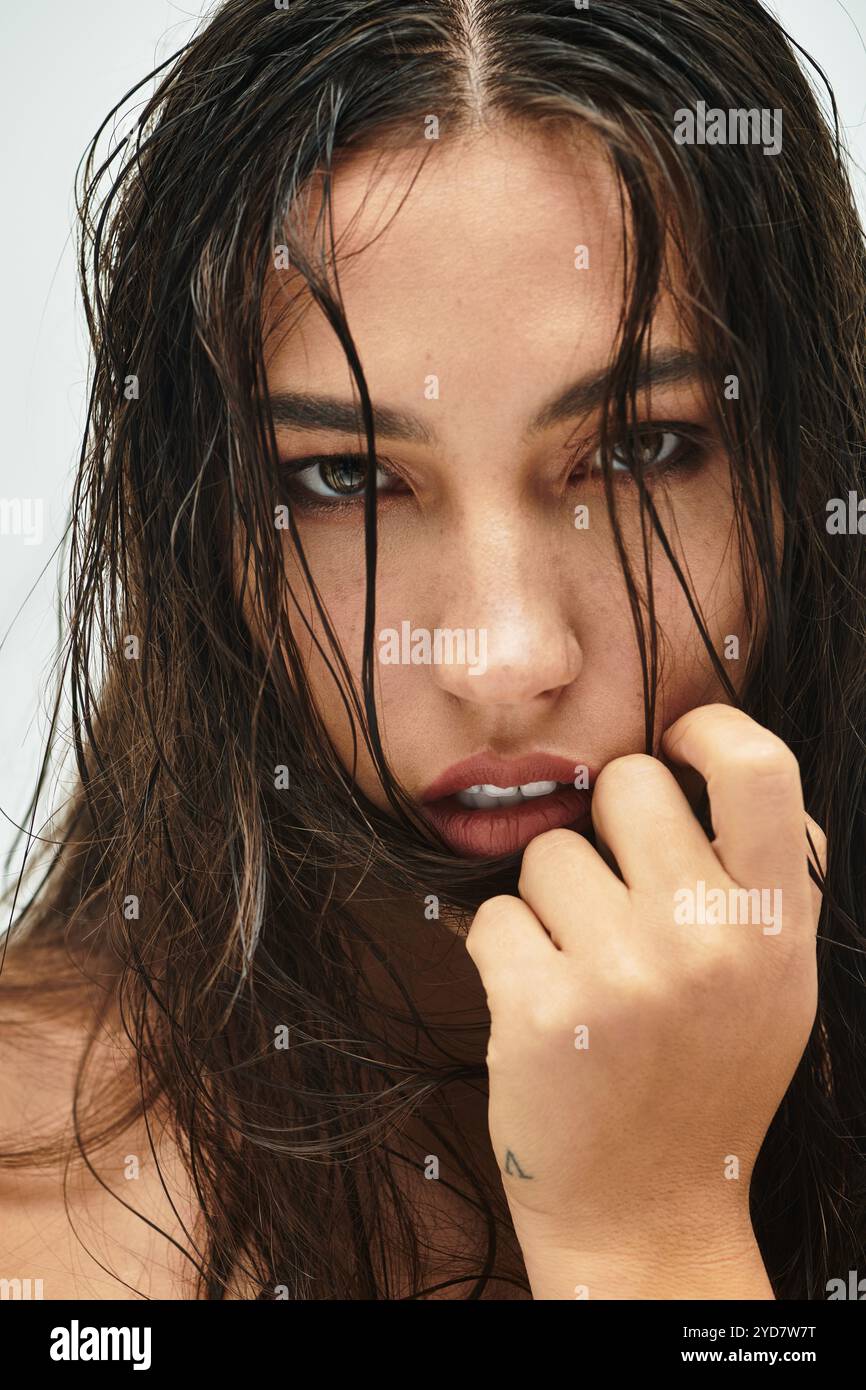 Un gros plan montre une femme aux cheveux mouillés, soulignant son regard captivant et sa beauté. Banque D'Images