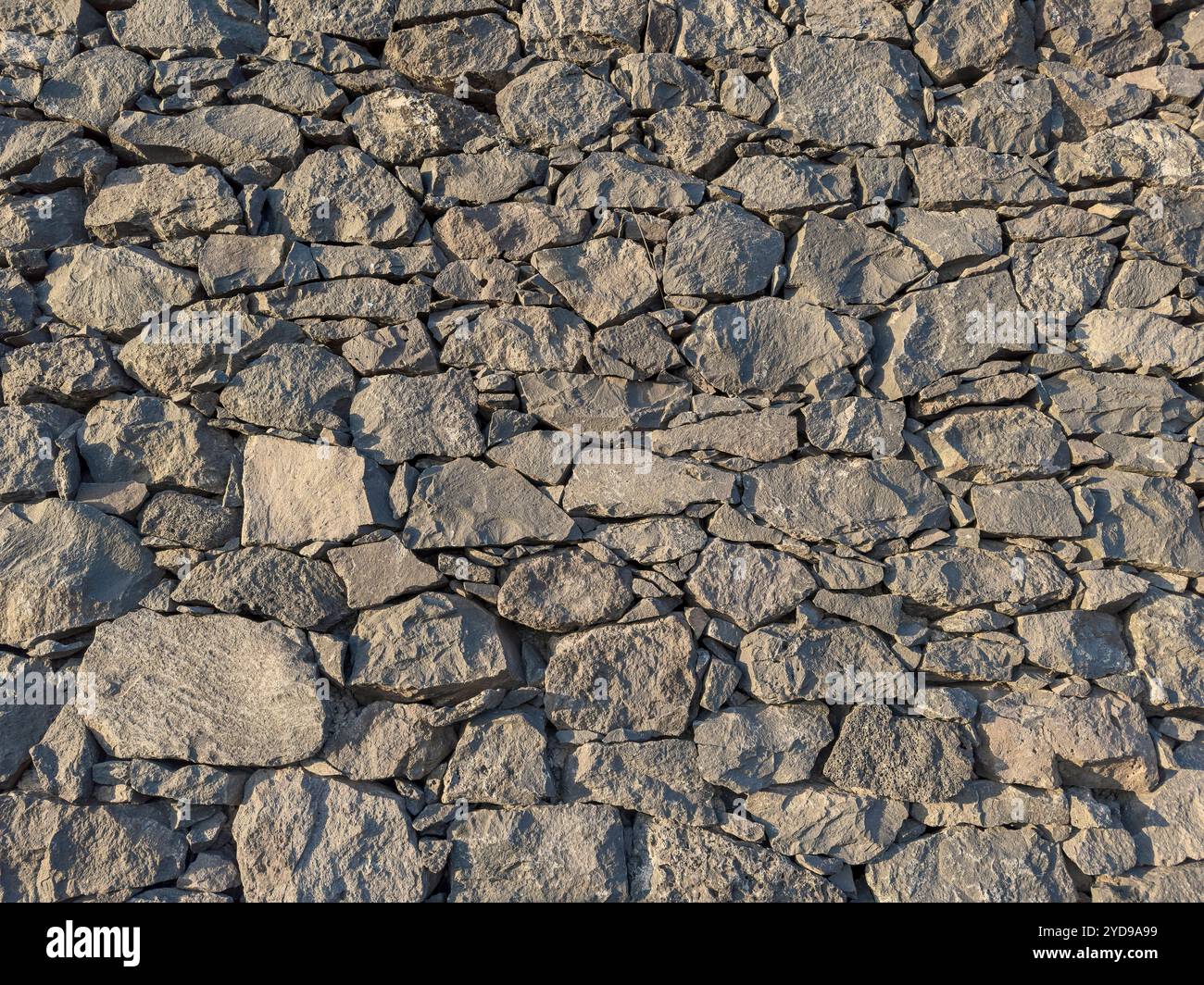 Fond d'un mur de pierre empilé fait de roches volcaniques de différentes tailles Banque D'Images