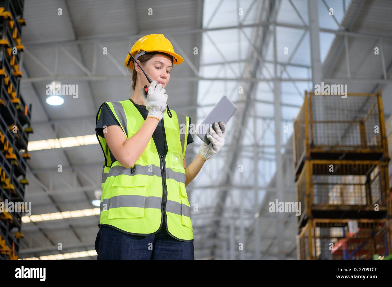 Travailleuse dans un entrepôt de pièces automobiles, examinez les pièces automobiles qui sont prêtes à être expédiées à l'usine d'assemblage automobile. Banque D'Images