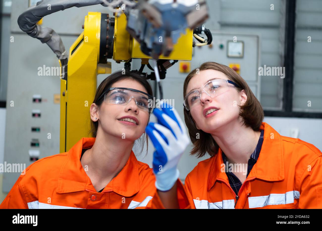 Dans une usine de pièces électroniques, deux femmes ingénieurs dans l'usine, inspectent et testent les mains robotiques utilisées dans la production Banque D'Images