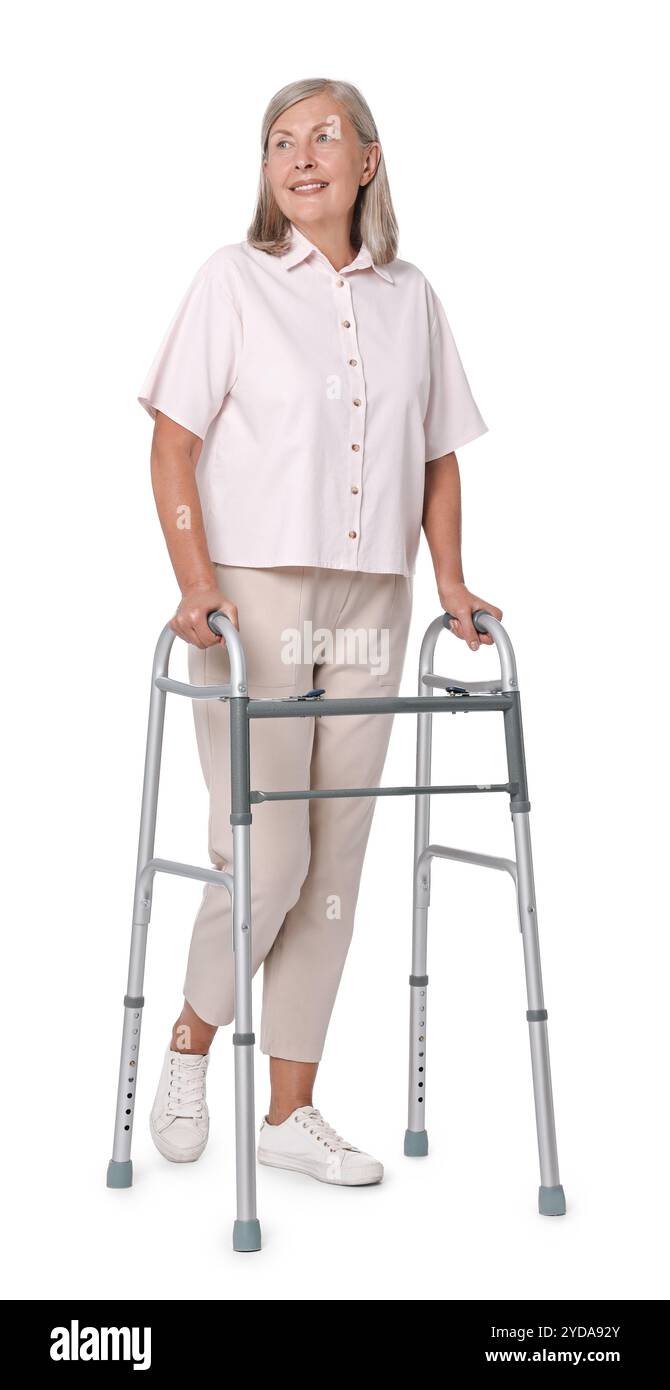 Femme senior utilisant le cadre de marche sur fond blanc Banque D'Images