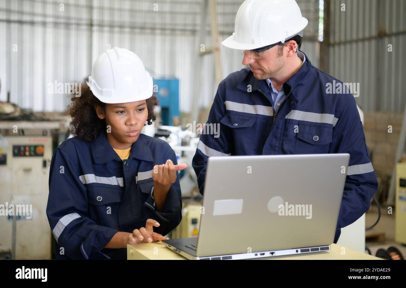 Les deux ingénieurs vérifient le fonctionnement des robots de soudage. Banque D'Images
