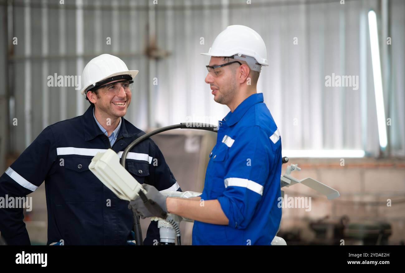 Les deux ingénieurs vérifient le fonctionnement des robots de soudage. Banque D'Images