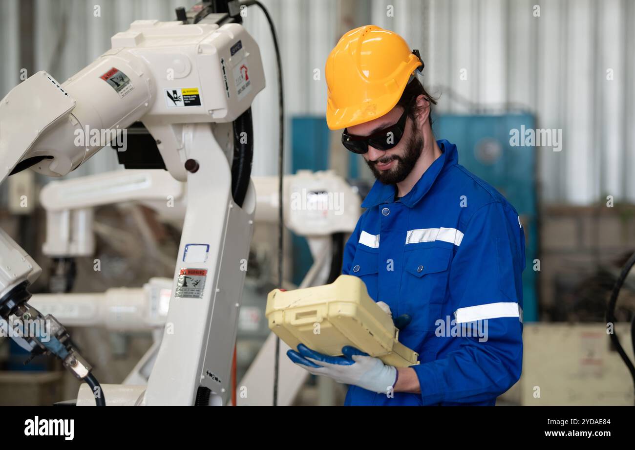 De jeunes ingénieurs masculins manipulent une main de robot de soudage. En combinant la manipulation de soudage avec un panneau de commande pour des w Banque D'Images
