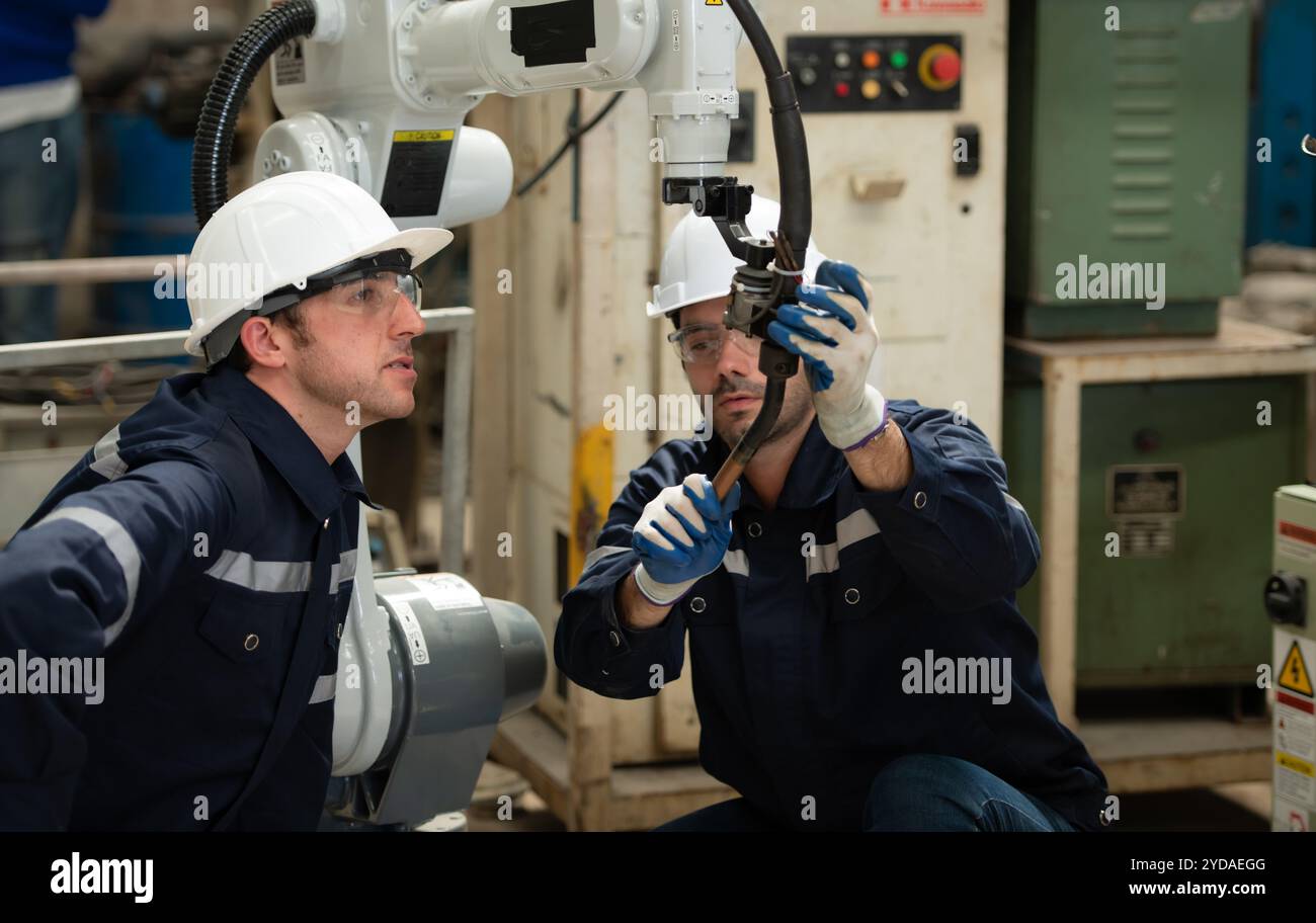 Les deux ingénieurs vérifient le fonctionnement des robots de soudage. Banque D'Images