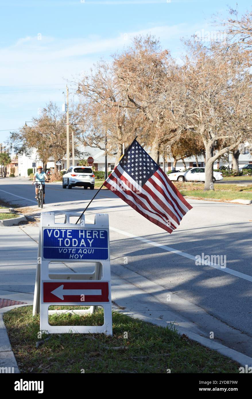 Venise, Floride, États-Unis – 24 octobre 2024 : drapeau américain et tableau sandwich indiquant « votez ici aujourd'hui » avec une flèche pointant vers le lieu de vote. Banque D'Images