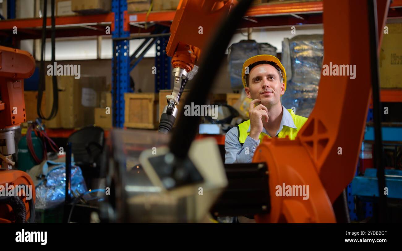 Un ingénieur vérifiant le fonctionnement d'un robot de soudage. Utilisé pour le contrôle de soudage de précision rapide et hautement sécurisé Banque D'Images