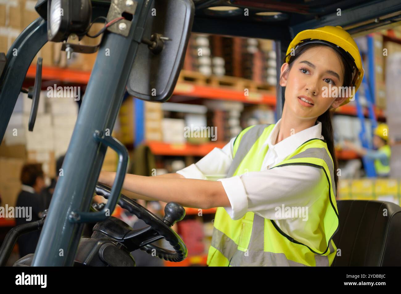 Travailleuse conduisant un chariot élévateur à fourche déplaçant des marchandises dans l'entrepôt pratiquant le fonctionnement du chariot élévateur Banque D'Images