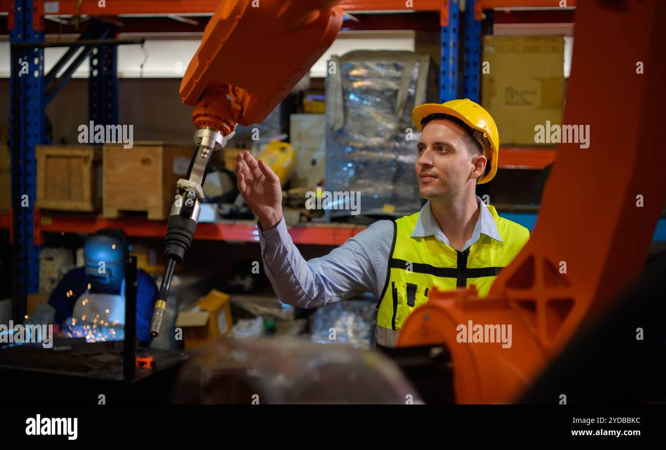 Un ingénieur vérifiant le fonctionnement d'un robot de soudage. Utilisé pour le contrôle de soudage de précision rapide et hautement sécurisé Banque D'Images