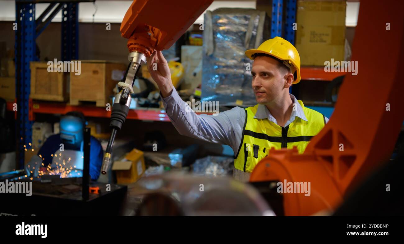 Un ingénieur vérifiant le fonctionnement d'un robot de soudage. Utilisé pour le contrôle de soudage de précision rapide et hautement sécurisé Banque D'Images