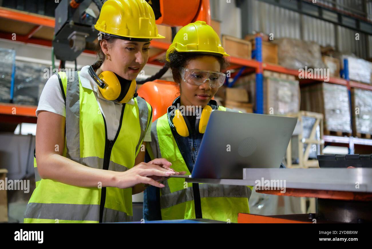 Deux femmes ingénieur vérifiant le fonctionnement d'un robot de soudage. Utilisé pour le contrôle de soudage de précision rapide et hautement sécurisé Banque D'Images