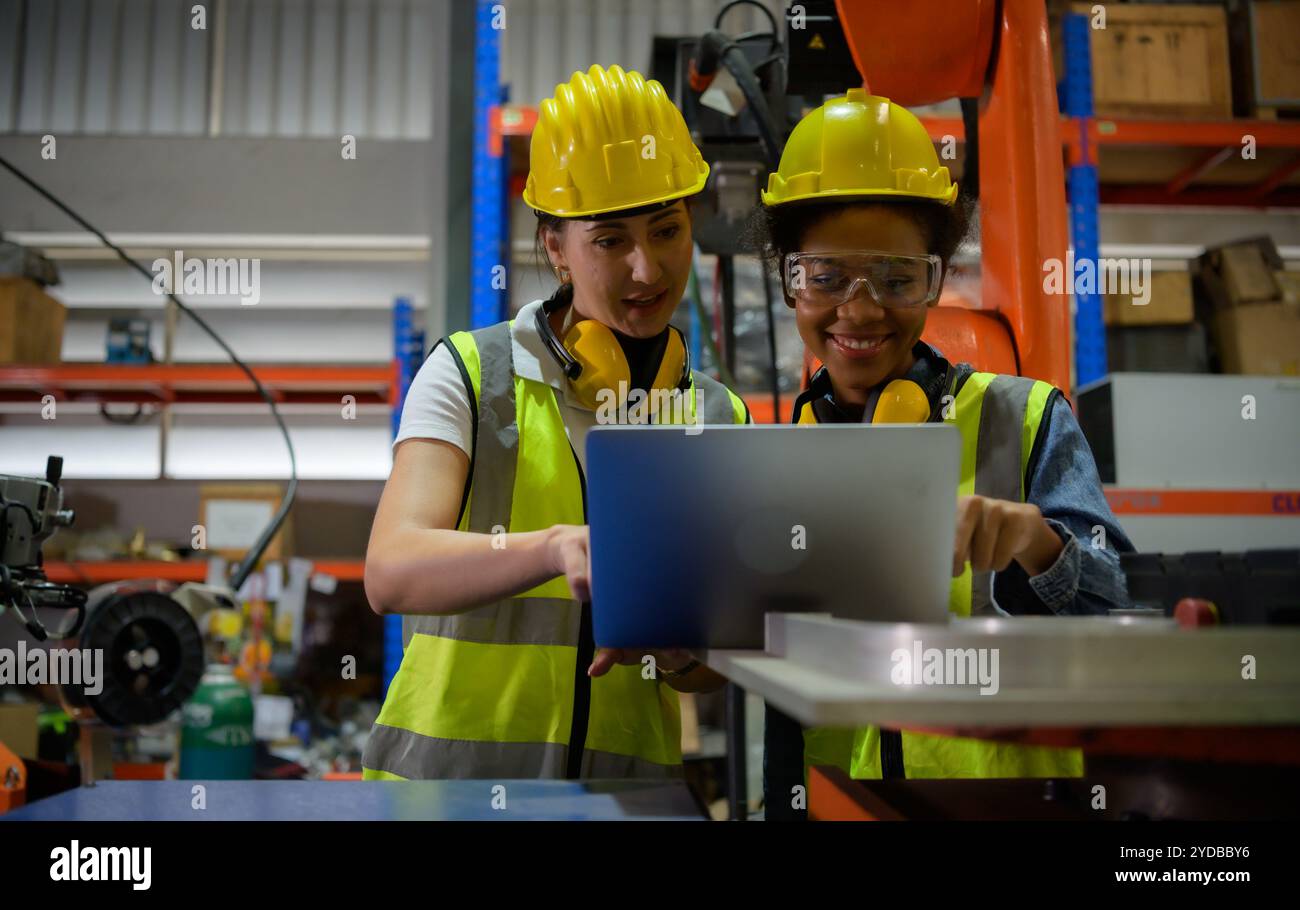 Deux femmes ingénieur vérifiant le fonctionnement d'un robot de soudage. Utilisé pour le contrôle de soudage de précision rapide et hautement sécurisé Banque D'Images