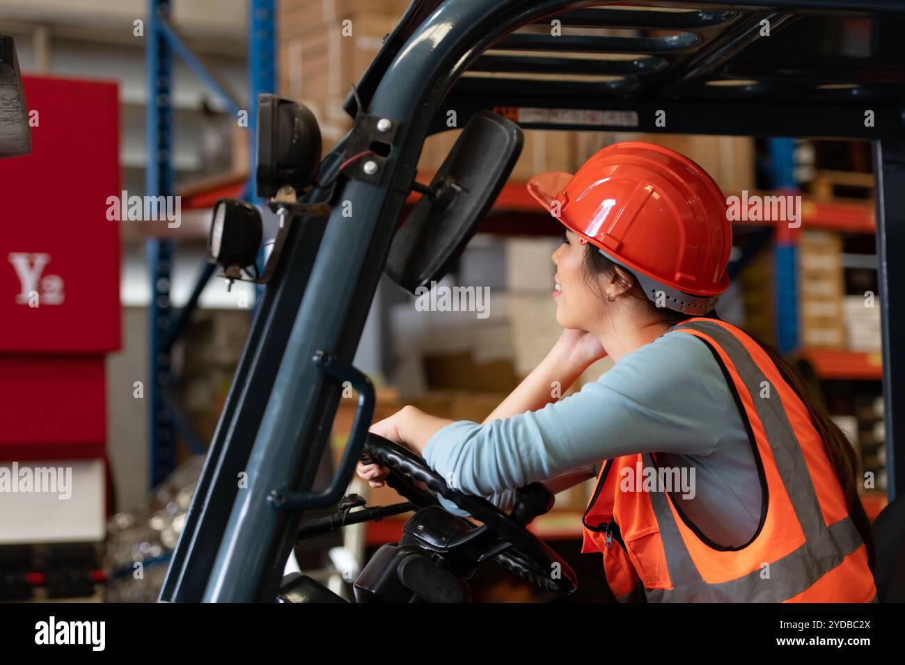 Portrait d'une femme asiatique avec un chariot élévateur utilisé pour soulever des objets lourds dans un entrepôt. Banque D'Images