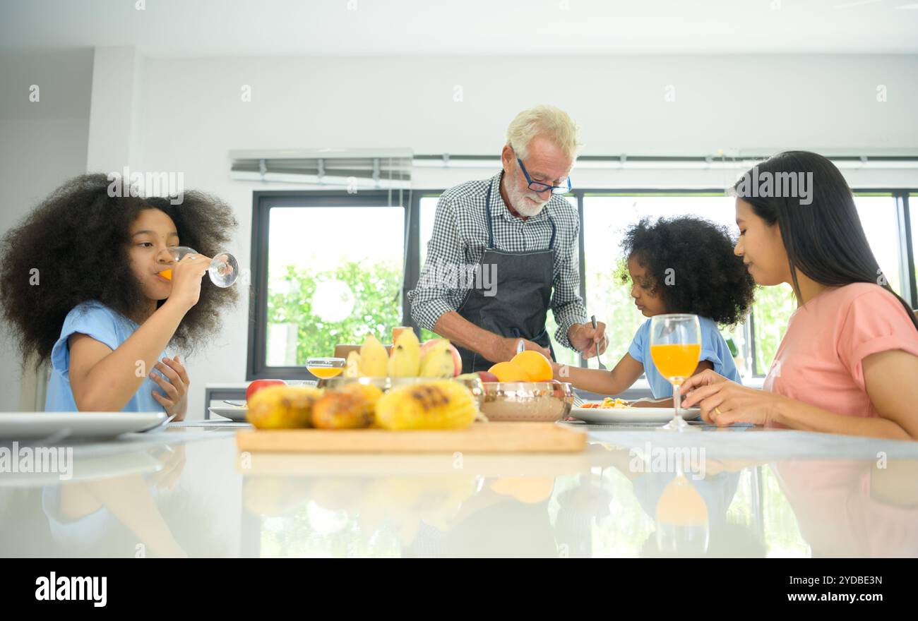 Famille afro-américaine asiatique ont un Happy Meal ensemble qui comprend grand-père, mère et enfants dans la salle à manger de t Banque D'Images