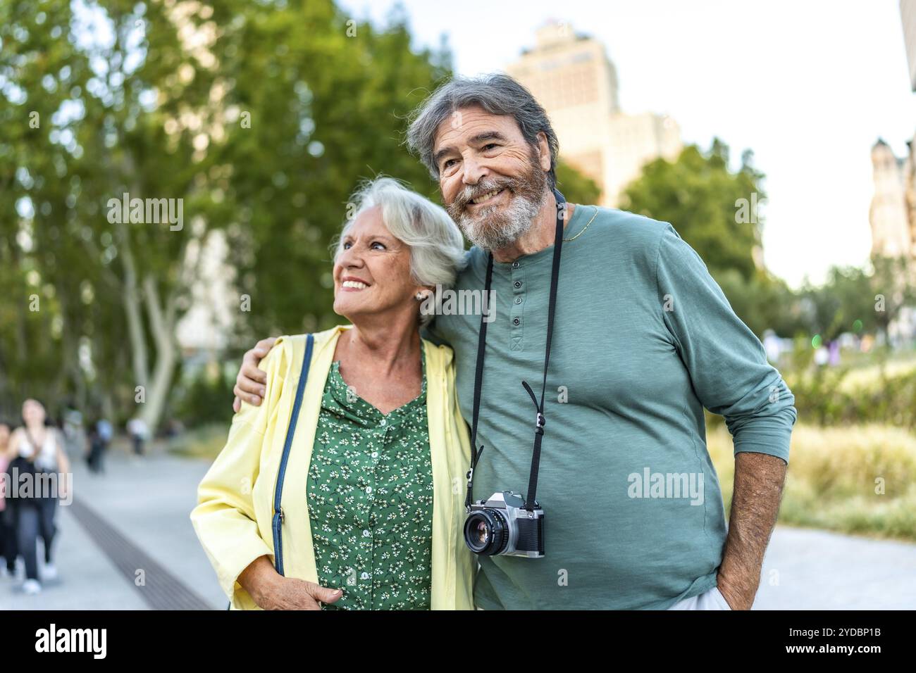 Heureuse femme aînée embrassée à l'homme avec un appareil photo dans un parc Banque D'Images
