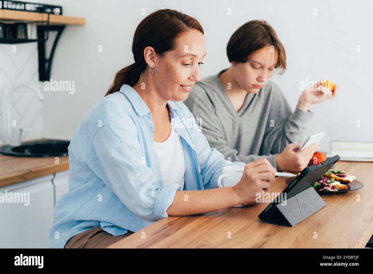Maman travaille sur une tablette numérique Banque D'Images