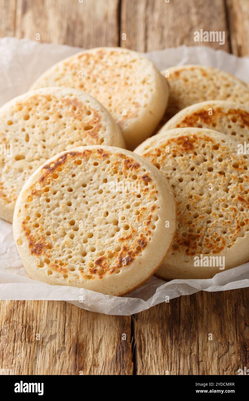 Grillé avec Butter Crumpet est un petit pain rond fait de pâte poreuse gros plan sur parchemin sur la table. Vertical Banque D'Images