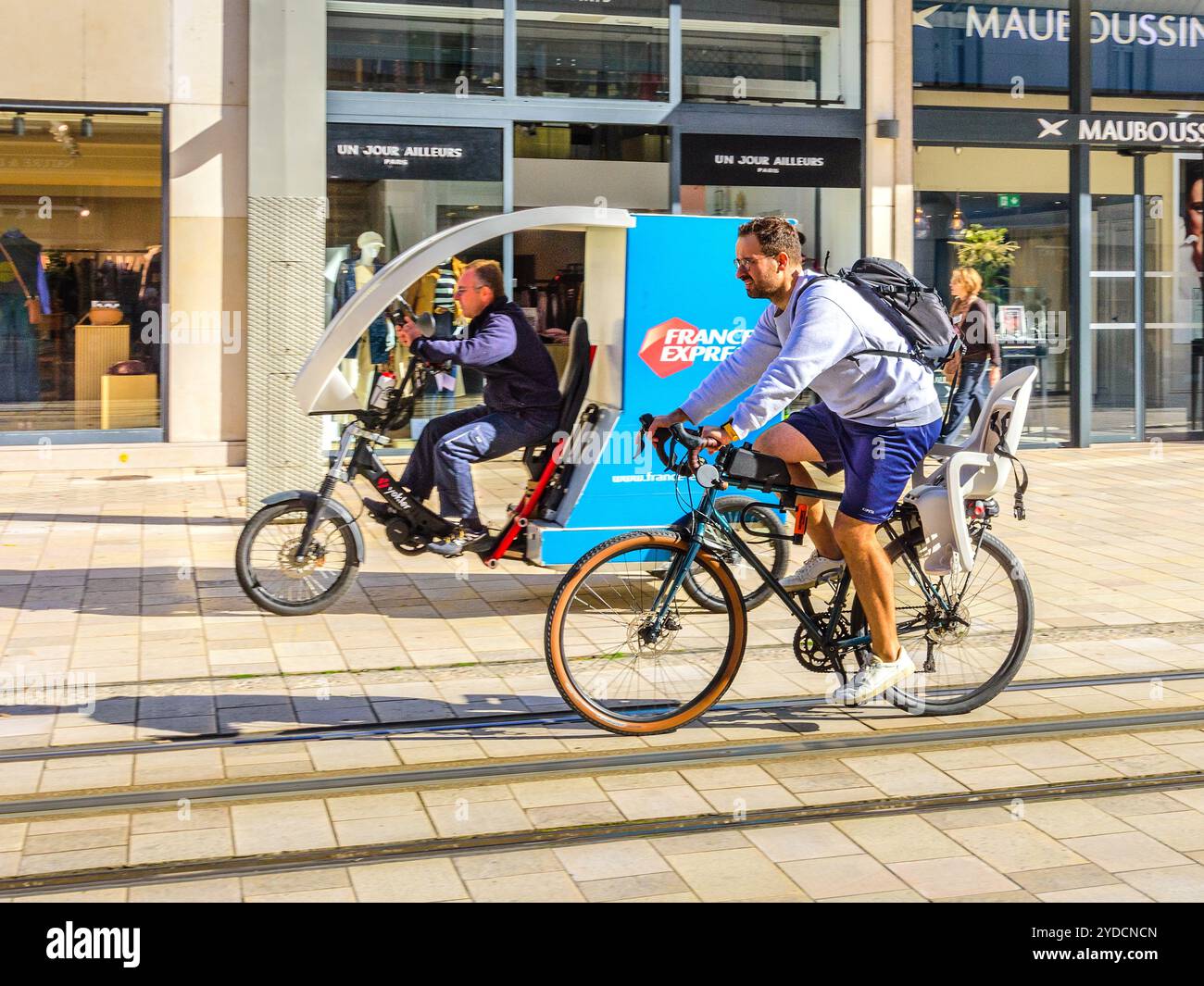 Homme à vélo à côté du tramway sur la rue non-véhicule du centre-ville - Tours, Indre-et-Loire (37), France. Banque D'Images