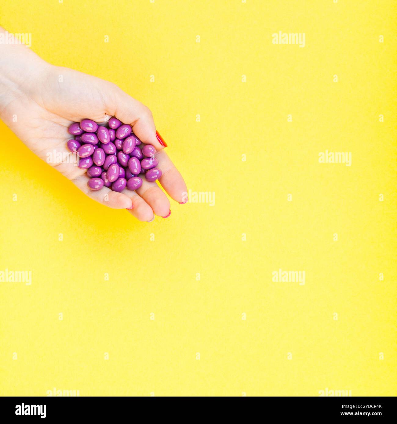 Main de femme tenant des pilules violettes poignée Banque D'Images