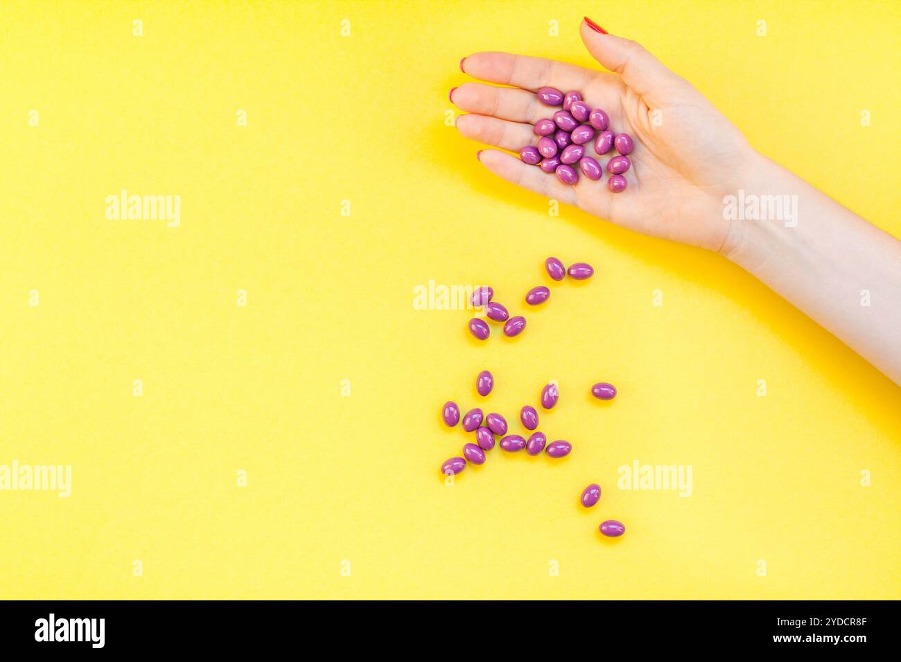 Main de femme tenant des pilules violettes poignée Banque D'Images
