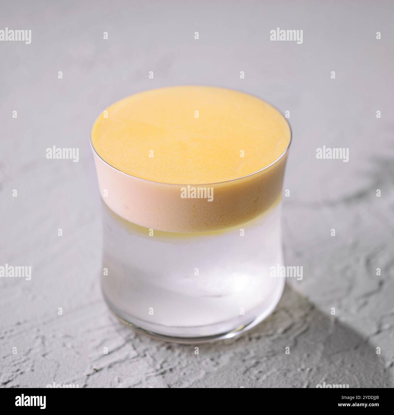Élégant verre à cocktail noix de coco avec mousse jaune Banque D'Images