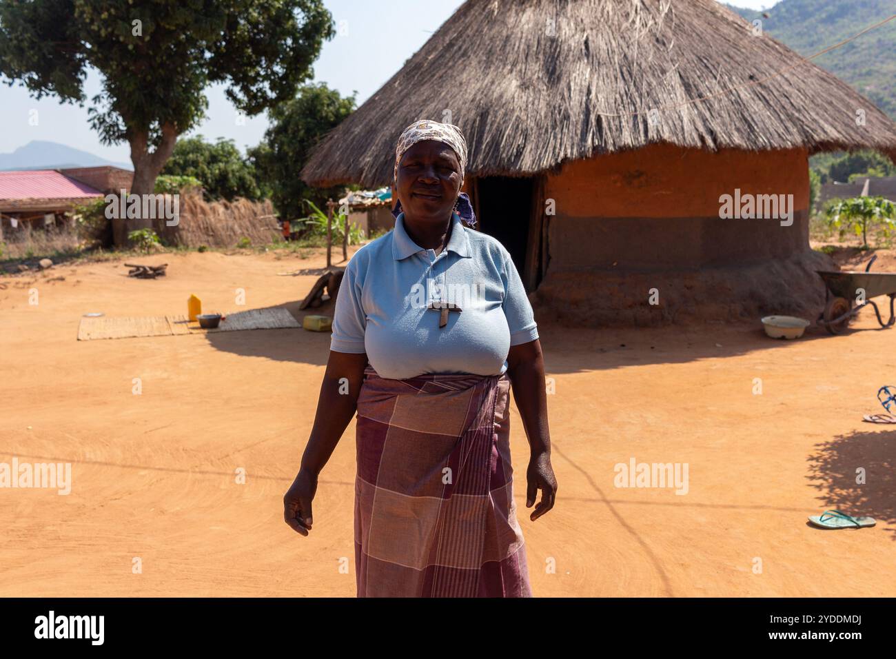 Femme debout devant une cabane de boue africaine traditionnelle, construite à partir d'argile et de foin Banque D'Images