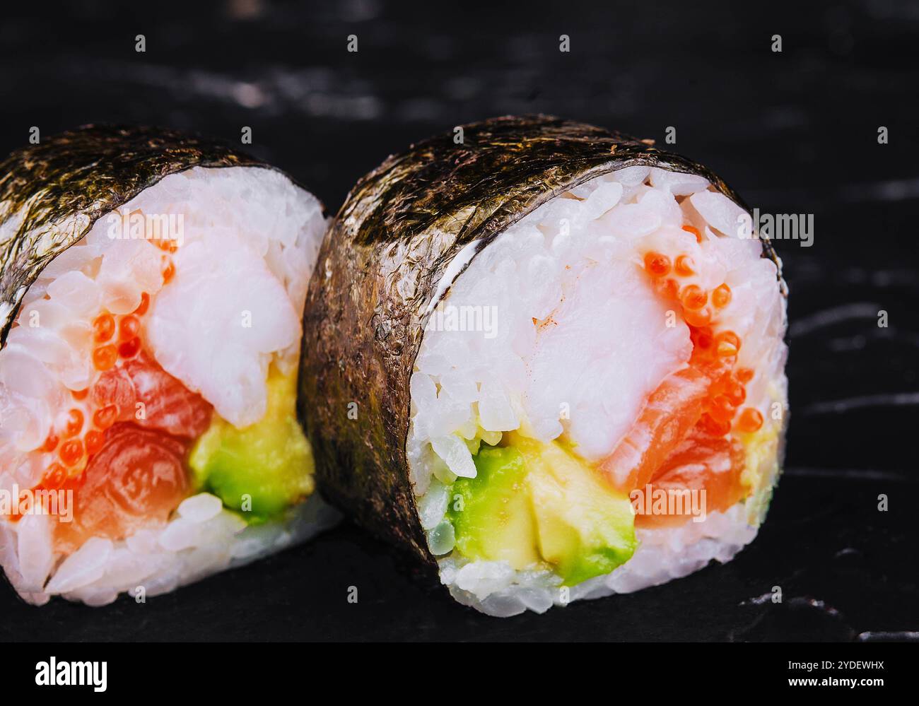 Sushi japonais frais traditionnel futomaki sur pierre noire Banque D'Images
