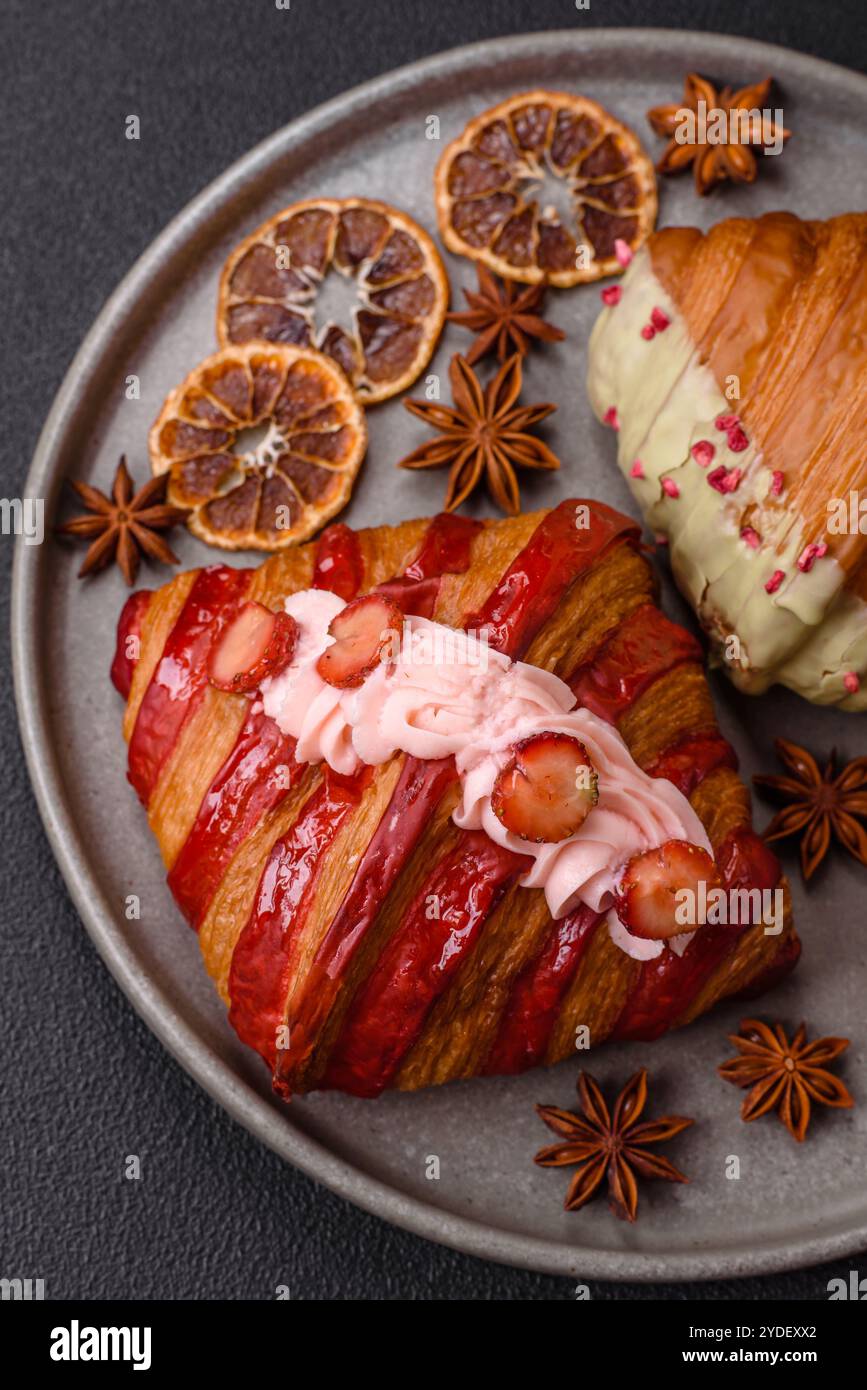 Croissant rouge sucré croustillant à la pistache, à la framboise et à la fraise sur un fond de béton foncé Banque D'Images